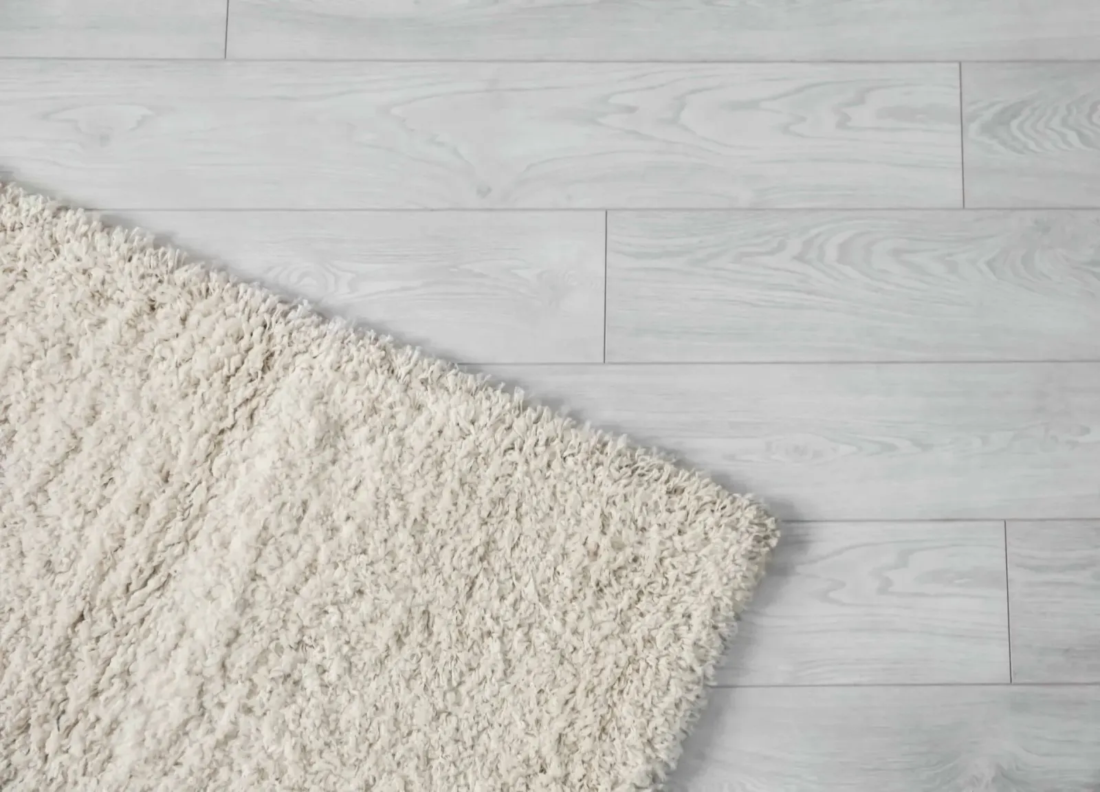 A white rug is laying on a white wooden floor.