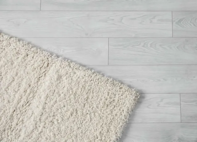 A white rug is laying on a white wooden floor.