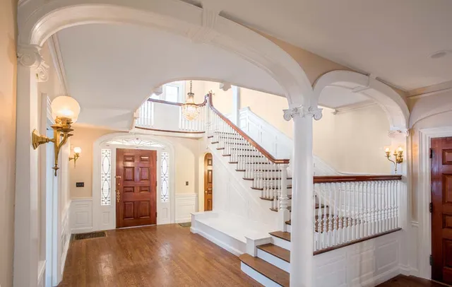 A large open foyer with a staircase and arched doorway.