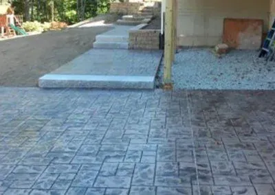 A concrete driveway with stairs leading up to a house.
