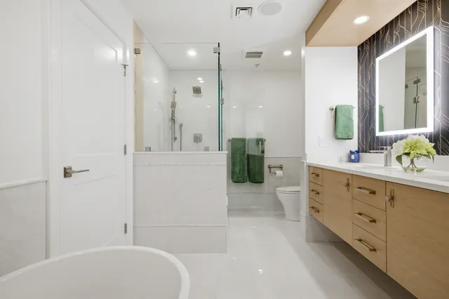 Braintree primary bath with a walk-in glass shower, freestanding tub, oak vanity, and a separate water closet area.