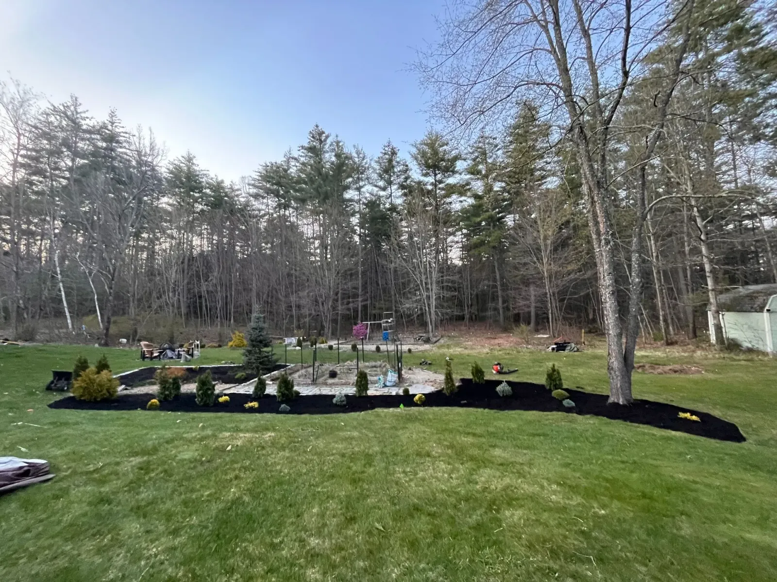 A backyard with a lush green lawn and trees in the background.