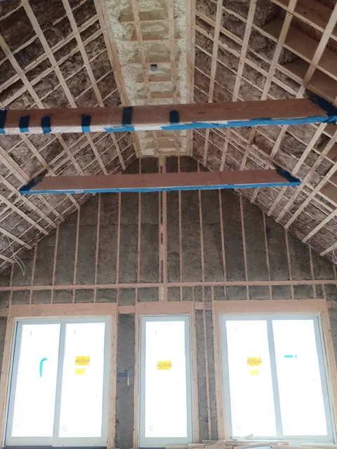 Vaulted lakehouse room with fiberglass batt insulation in walls and roof framing in New Hampshire