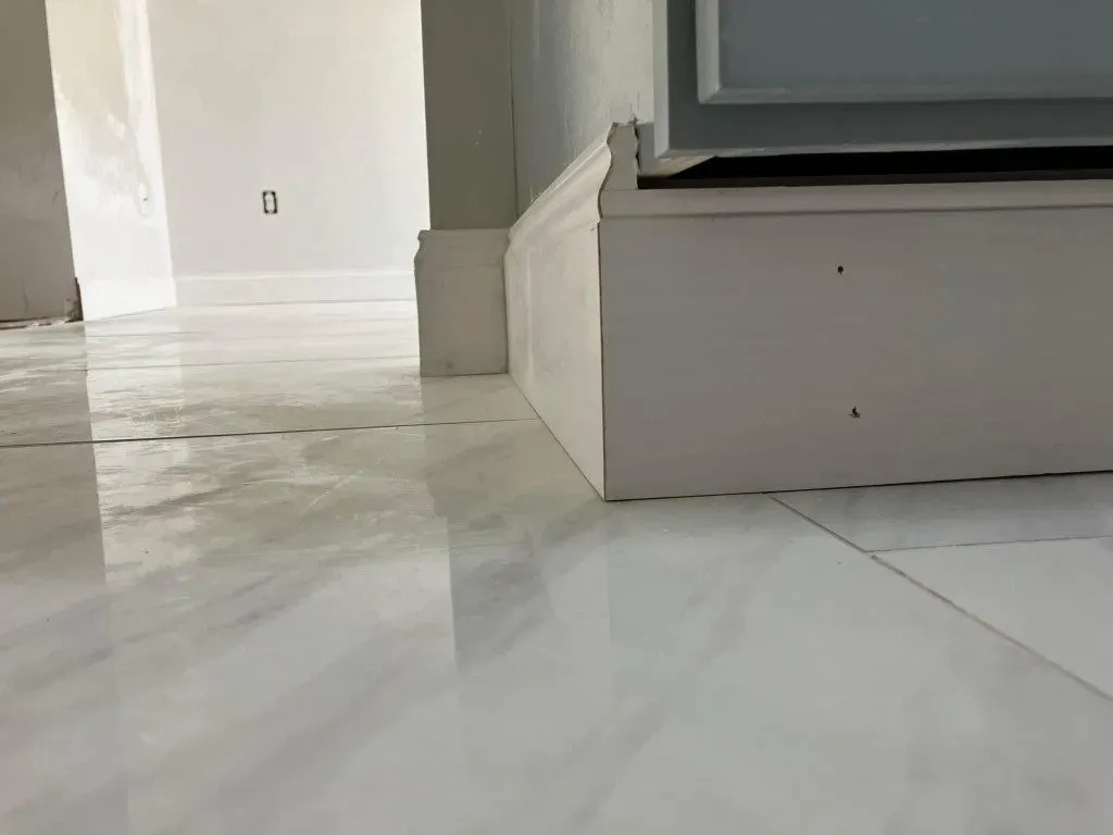 A close up of a white tile floor in a room.