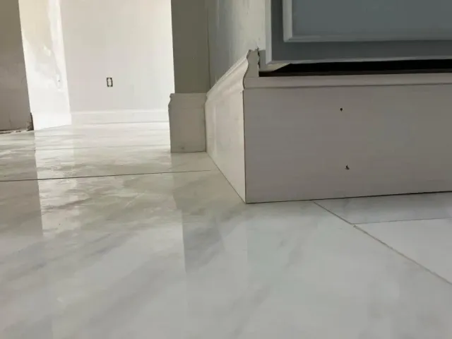 A close up of a white tile floor in a room.