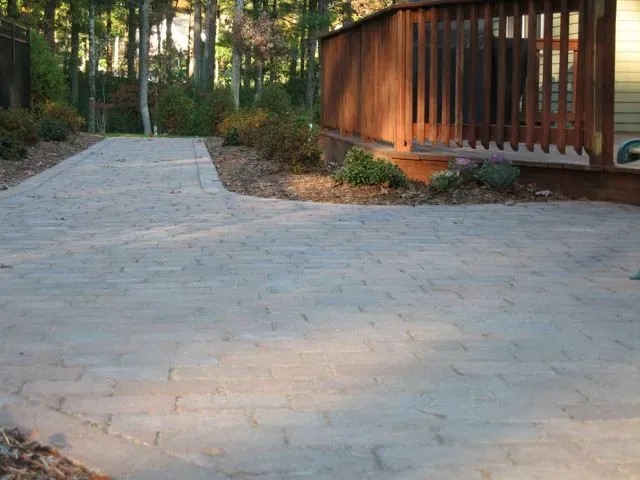 A driveway leading to a house with a wooden deck