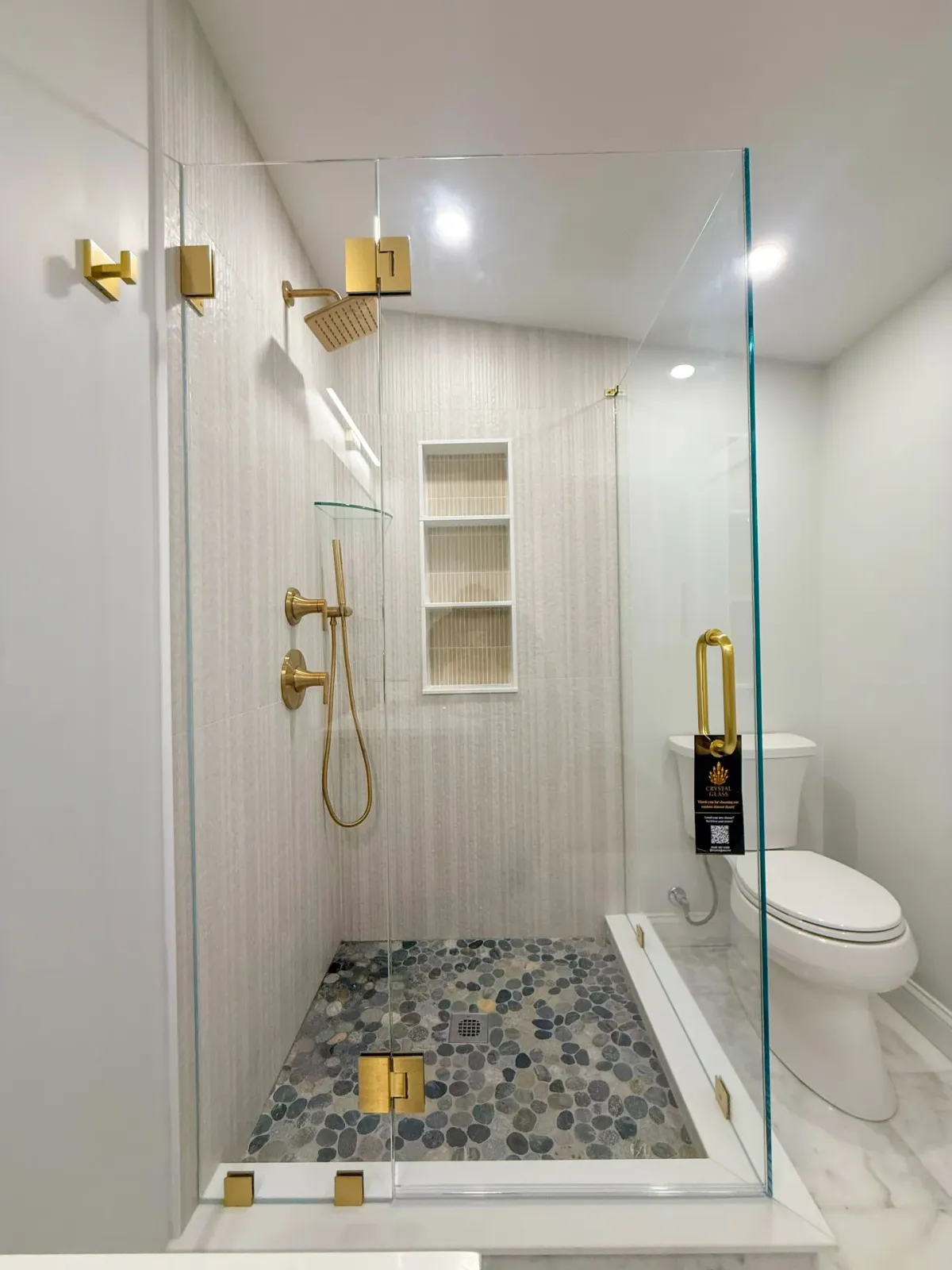 Frameless shower with gold hardware and pebble floor