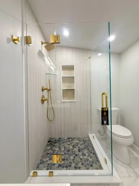Frameless shower with gold hardware and pebble floor
