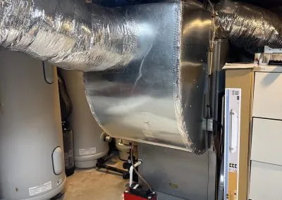 Completed geothermal heat pump system with ductwork and hot water tanks installed in Massachusetts home.