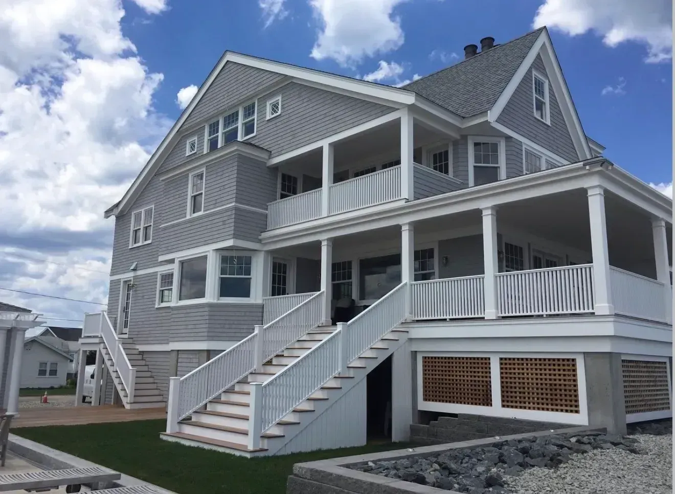 Completed gray shingle-style coastal home with white trim