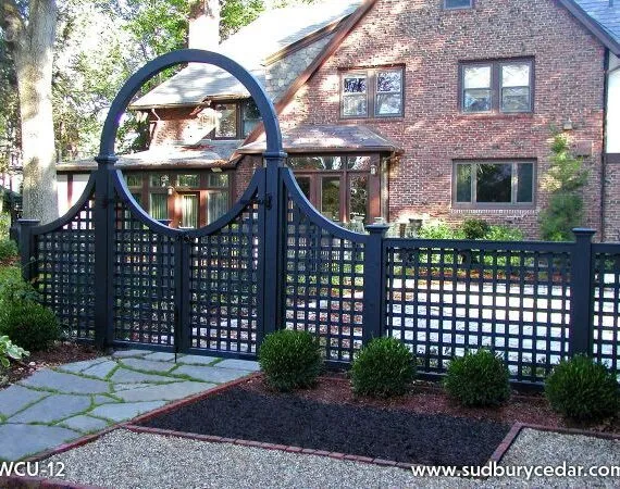 Lattice fence with an arched gate in front of a brick home, showcasing an elegant fence design that complements the home’s architecture.