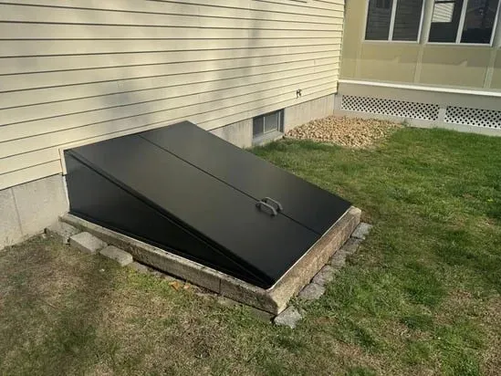 Final view of a repainted black basement door after exterior maintenance and refinishing.