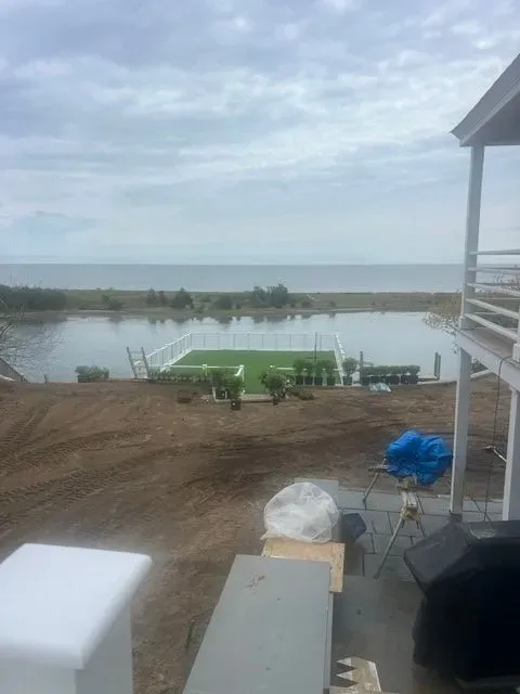 Riverfront dock with green benches, muddy shore, and a cloudy sky beside a white building