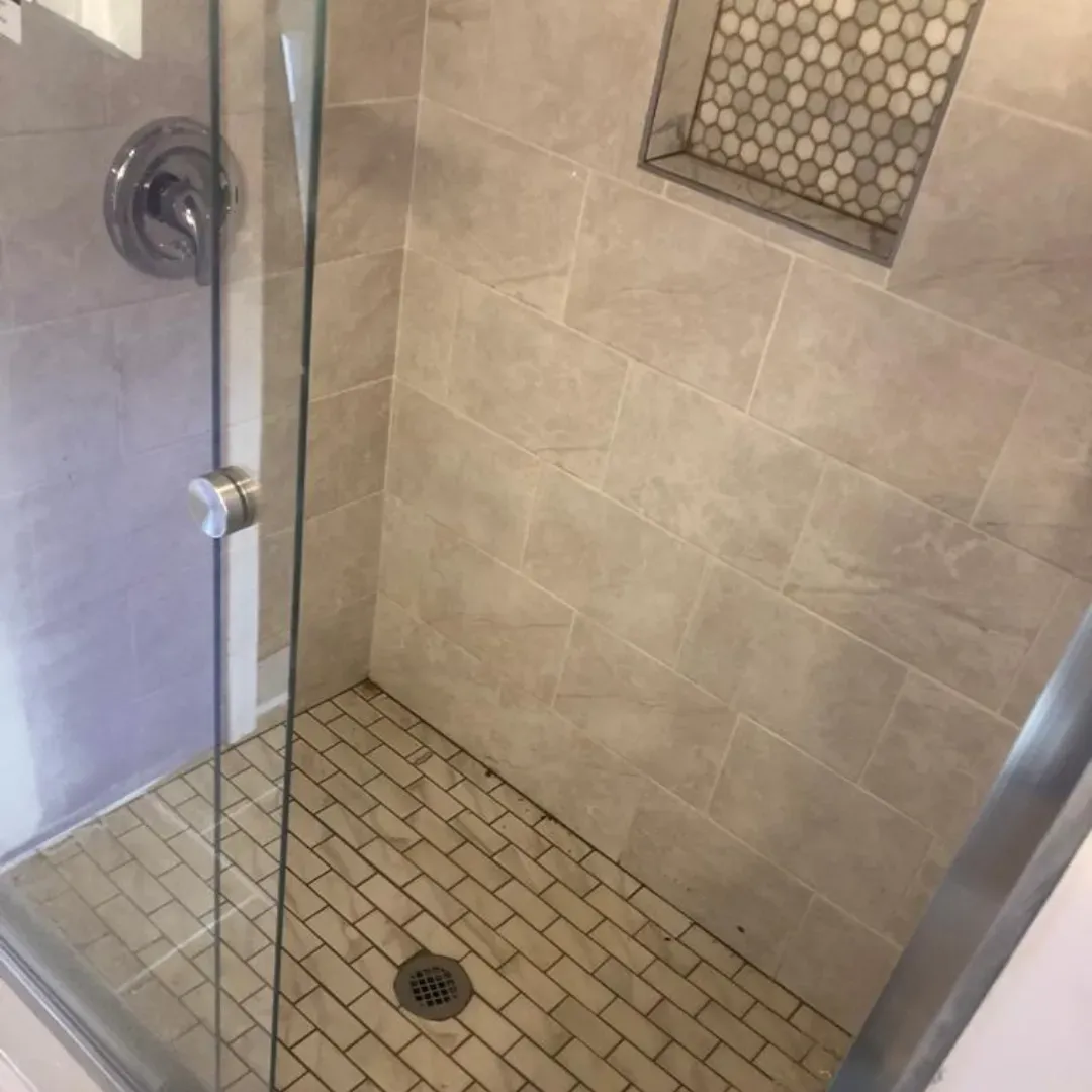Walk-in shower with travertine tile walls and brick pattern floor by Link Services Pro in Holden, MA