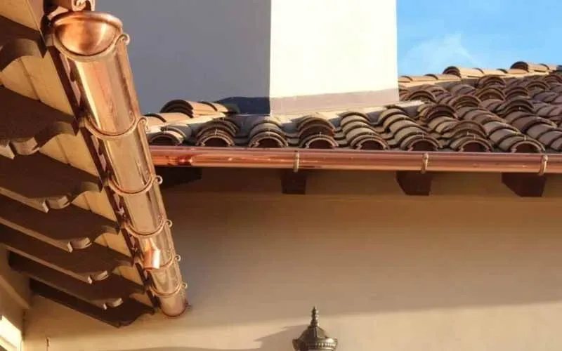 A copper gutter is attached to the roof of a building