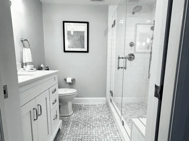 Modern bathroom with glass shower enclosure, white vanity, and tiled floor.