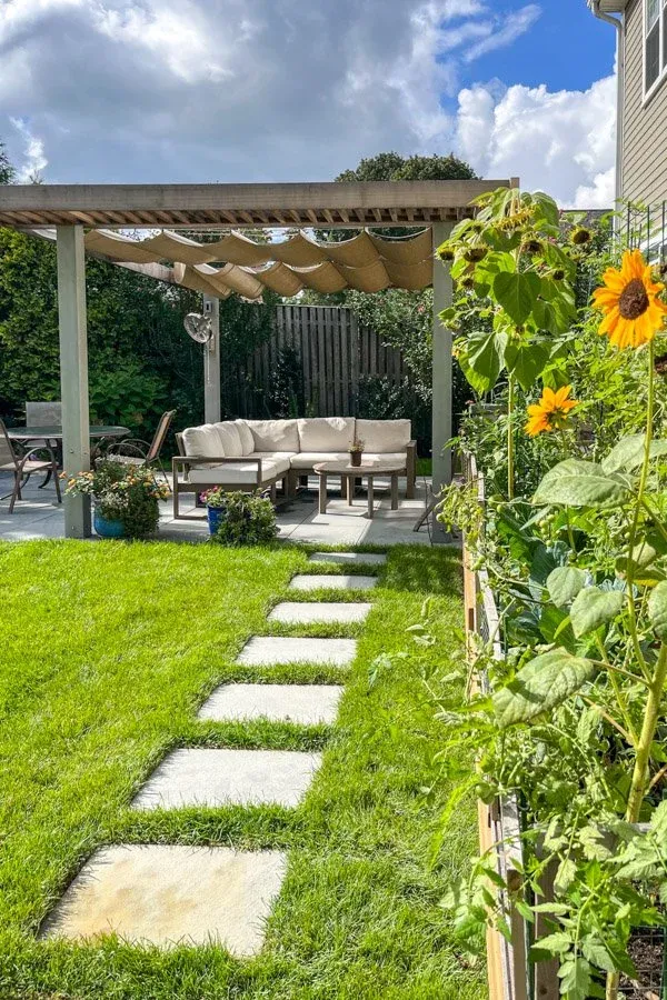 Wood and metal pergola with moveable fabric shades with raised garden beds