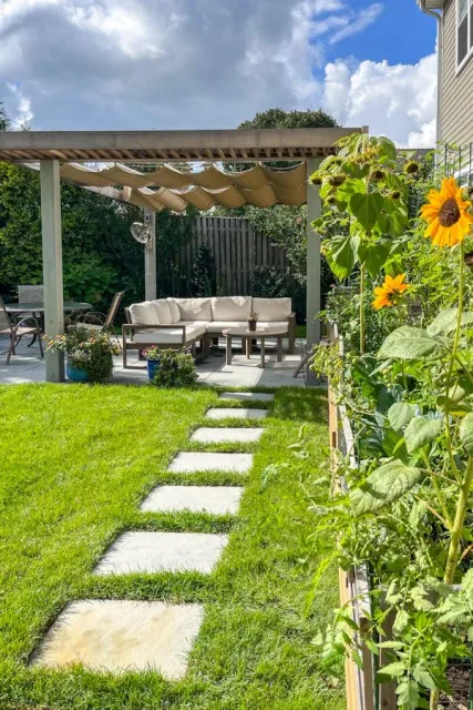Wood and metal pergola with moveable fabric shades with raised garden beds