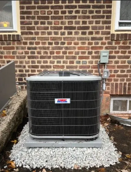 An air conditioner is sitting outside of a brick building
