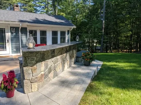 Outdoor stone bar with countertop, lanterns, and plant