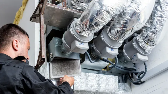 A man is working on a ventilation system in a building