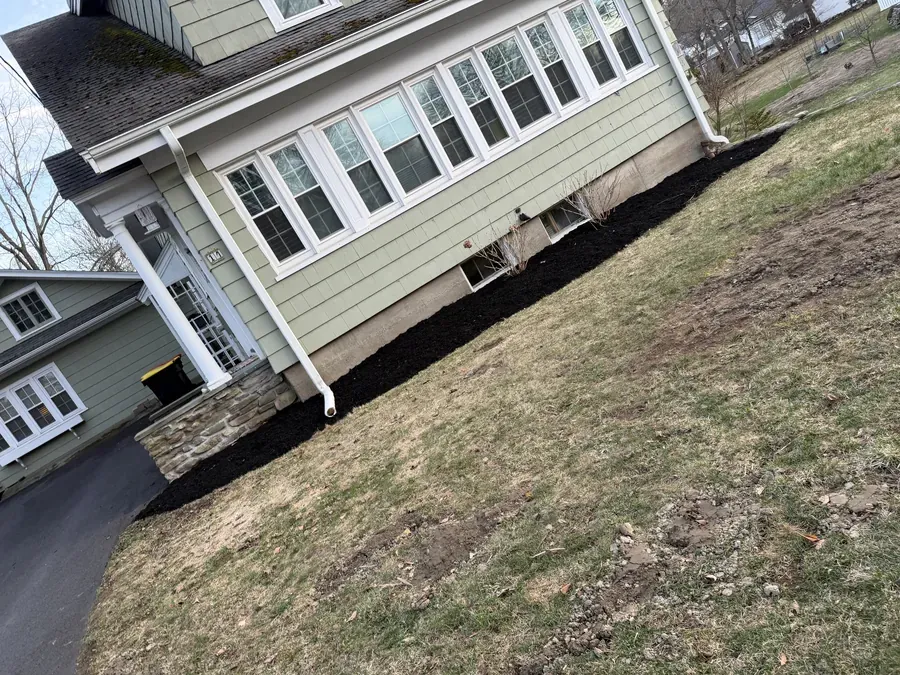 Fresh black mulch bed installed along home foundation by TB Lawn and Landscape