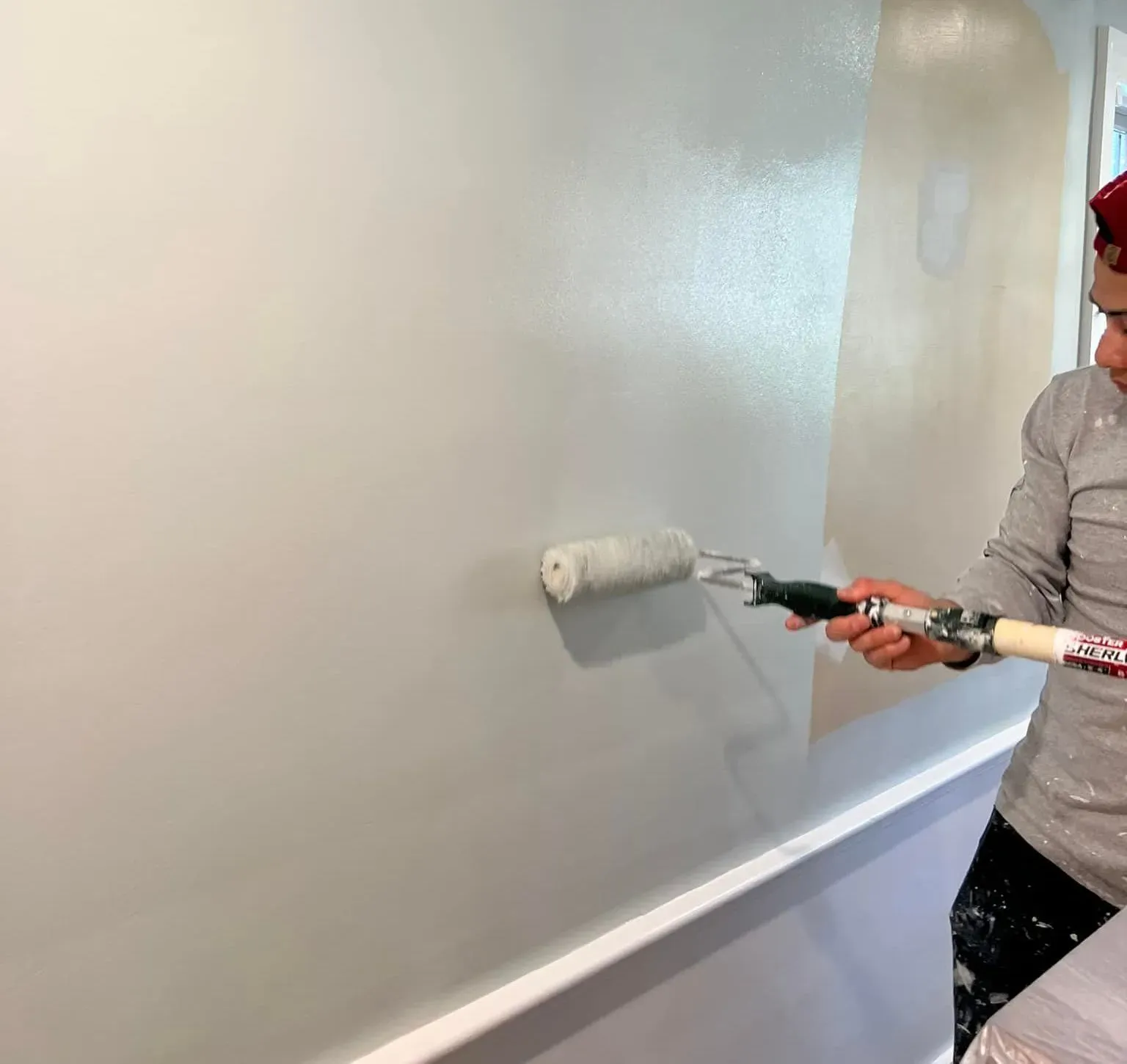A man is painting a wall with a paint roller