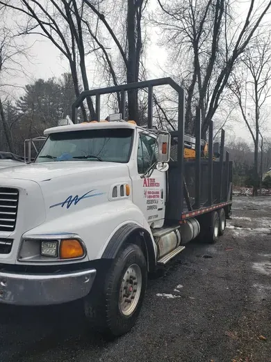 White dump truck parked on a wet road in a wooded area