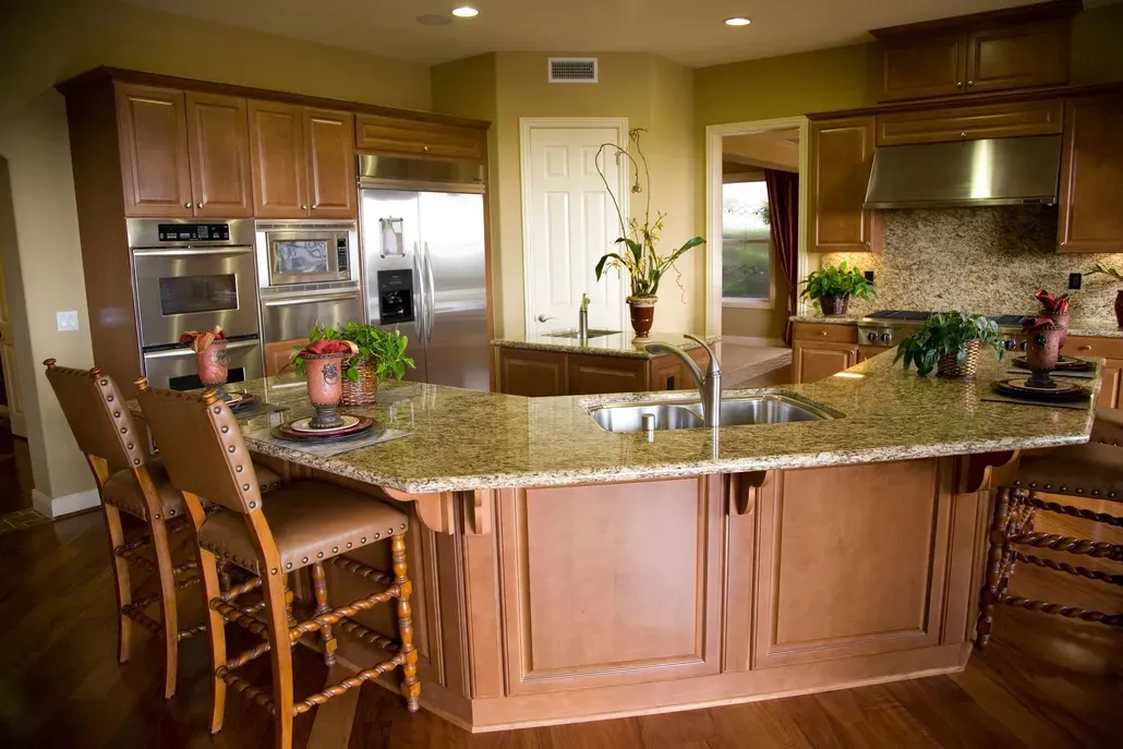 Modern kitchen with wood cabinets, granite island, and bar stools under warm lighting