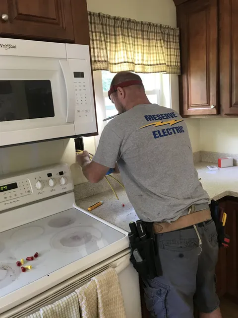 Electricians repairing kitchen appliances and residential wiring