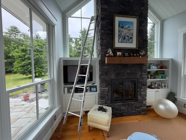 A ladder set up inside a great room with vaulted gable windows