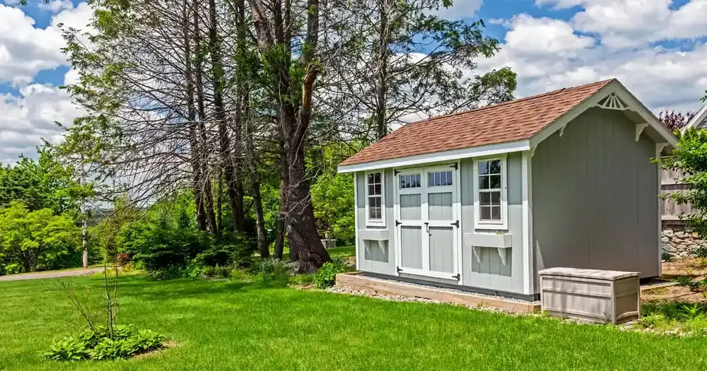 Custom backyard storage shed with double doors, windows, and shingle roof