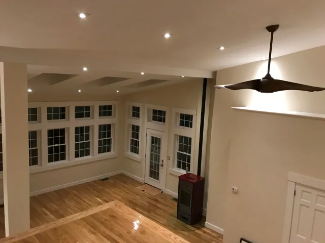 Modern living room with hardwood floors, large windows, ceiling fan, and recessed lighting.