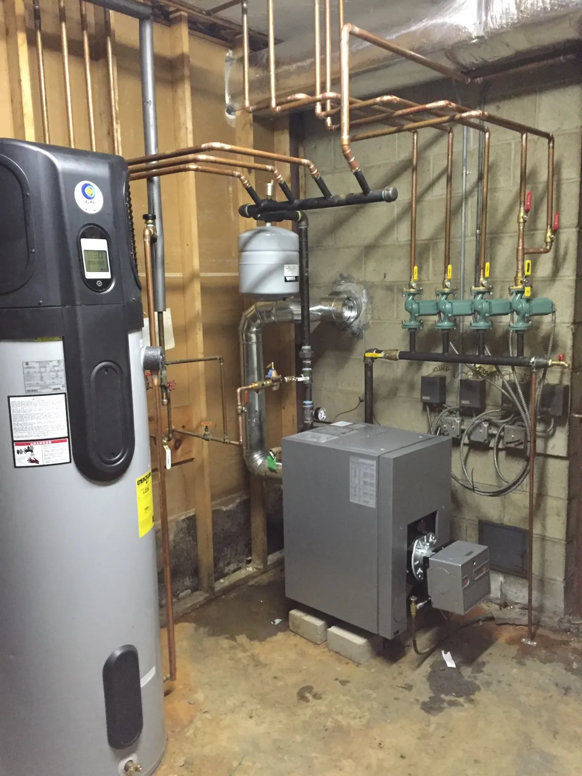 Basement utility room with a water heater, boiler, and piping system.