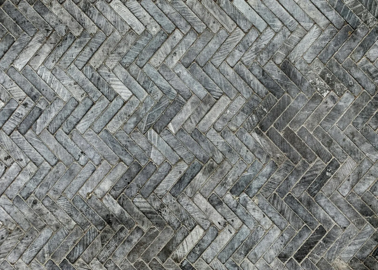 A close-up view of a herringbone-patterned wooden brick wall. Rooms With A View Tile