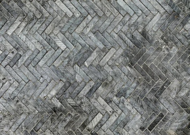 A close-up view of a herringbone-patterned wooden brick wall. Rooms With A View Tile