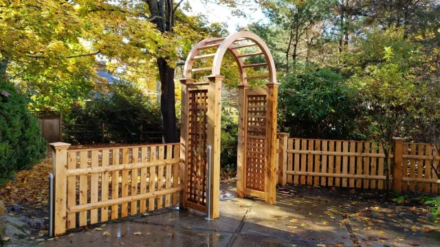 A wooden archway is surrounded by a wooden fence in a garden.