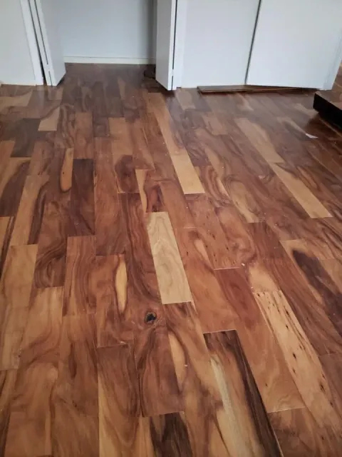 Wood plank flooring with varied brown tones, near white doors.