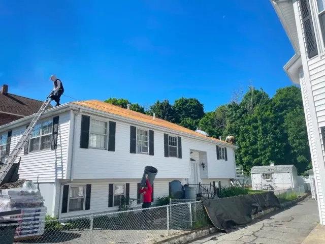 A man is standing on the roof of a white house.