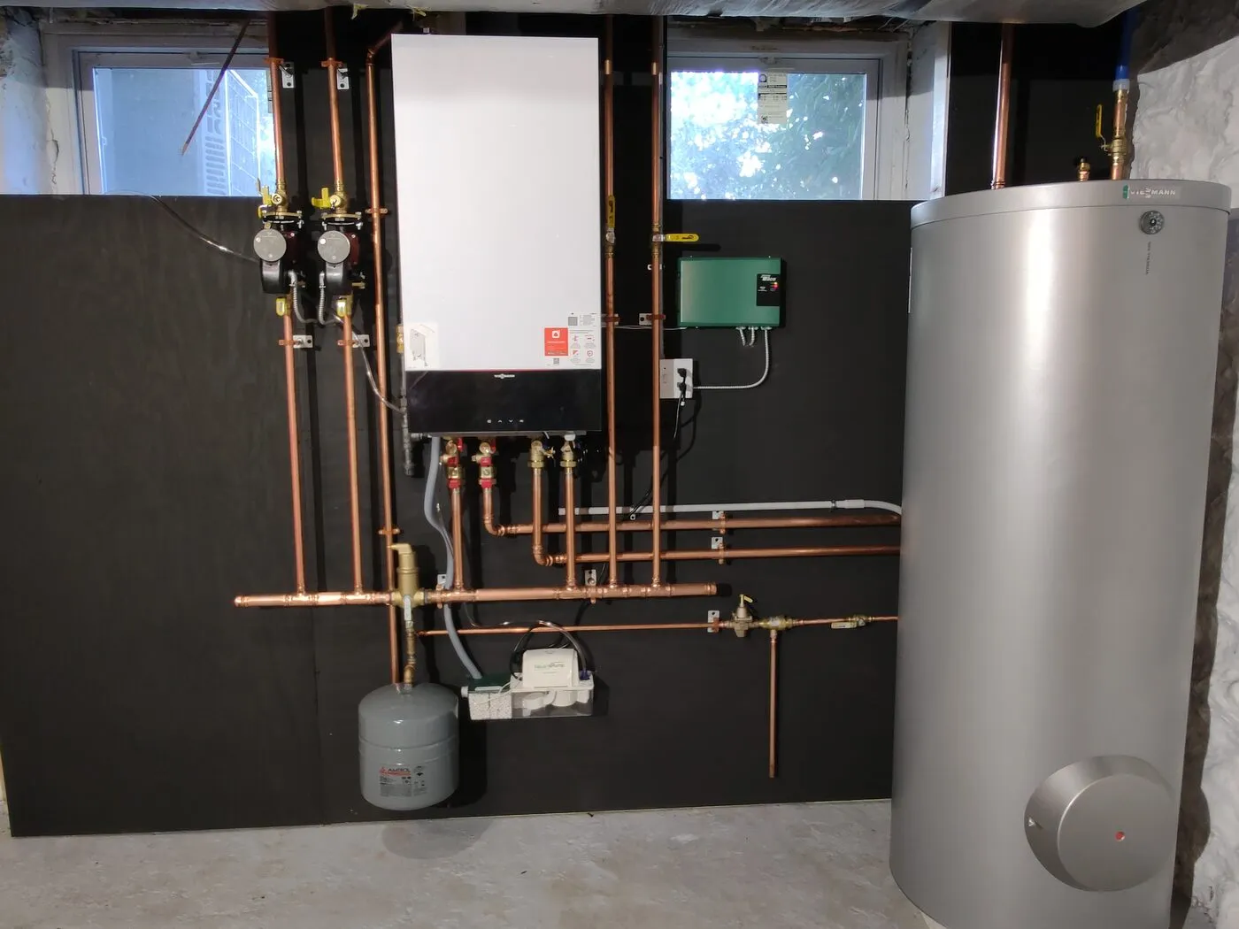 Tankless condensing boiler with a copper piping manifold and water heater tank installed by IS Plumbing