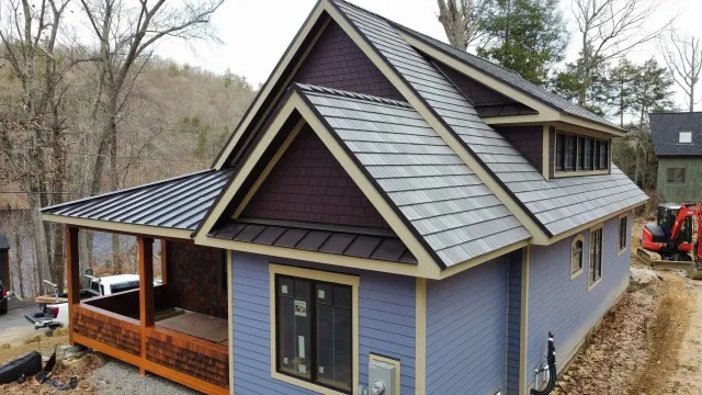 A small house with a slate roof is being built in the woods.