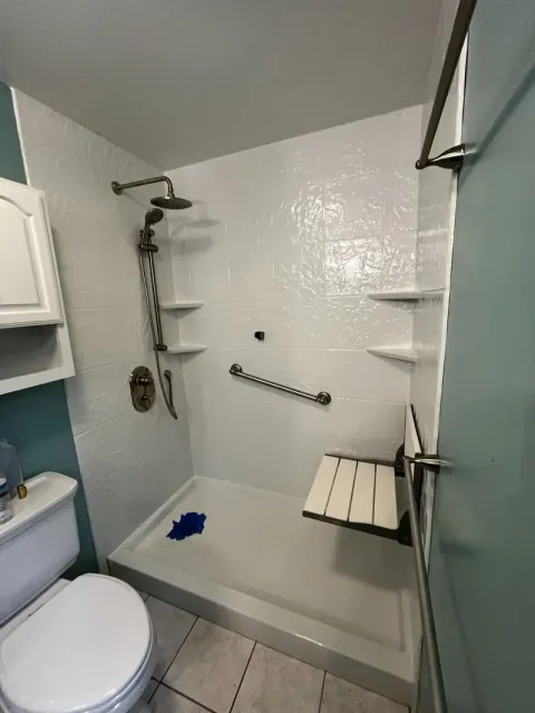 Finished acrylic shower with folding seat down, grab bar, sliding bar and rain head