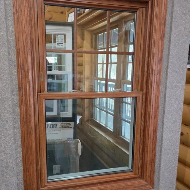 Wood-framed window looking into a narrow interior hallway with glass-paneled doors and a box inside.