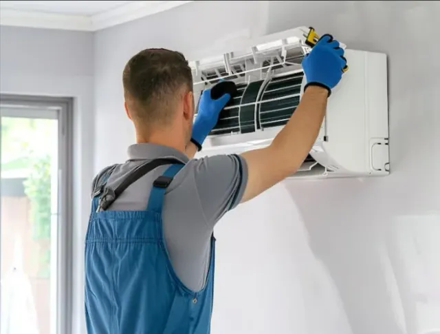 Technician model inspecting the filter area of a wall-mounted indoor air unit