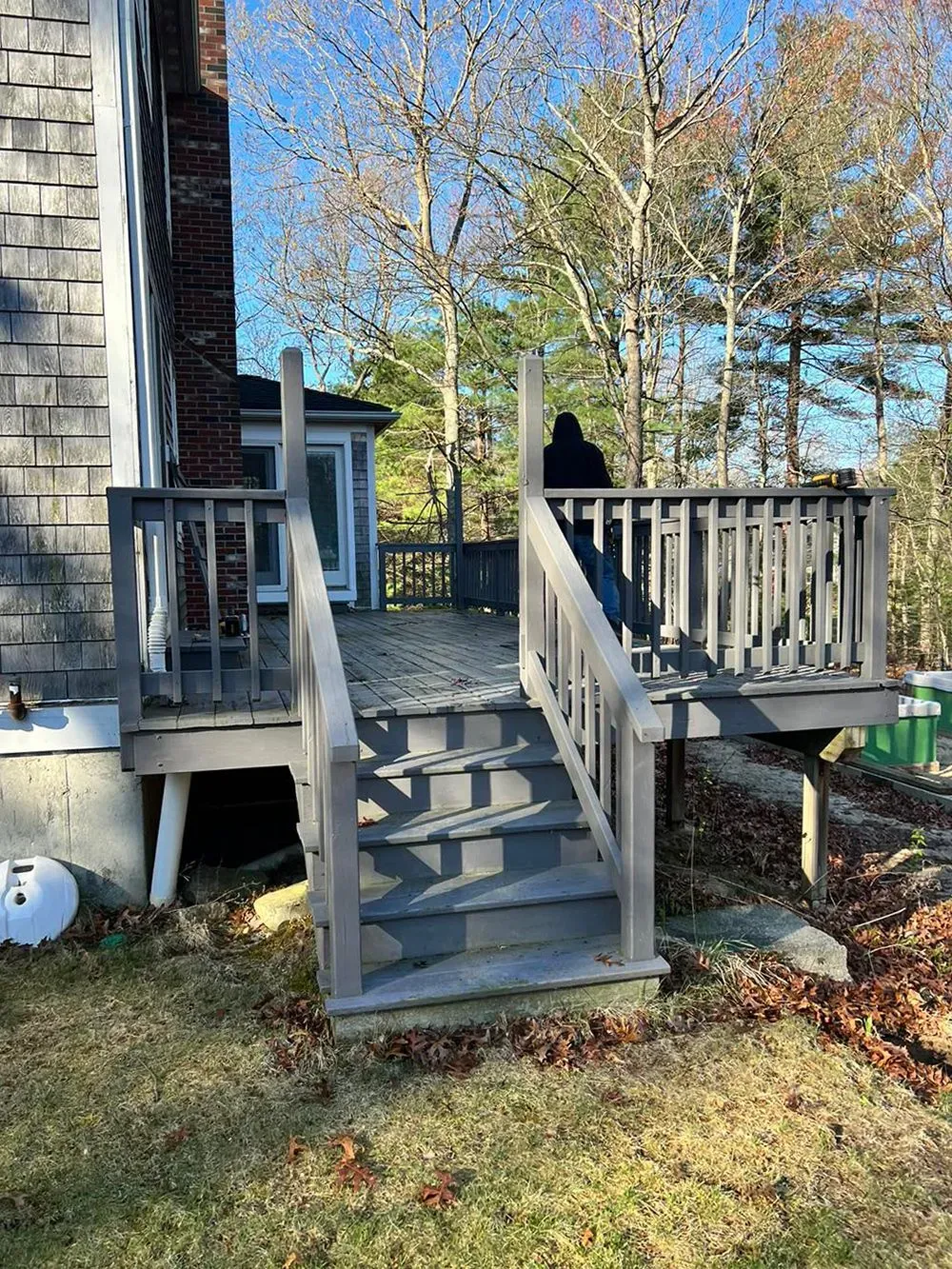 A wooden deck with stairs leading up to it in front of a house