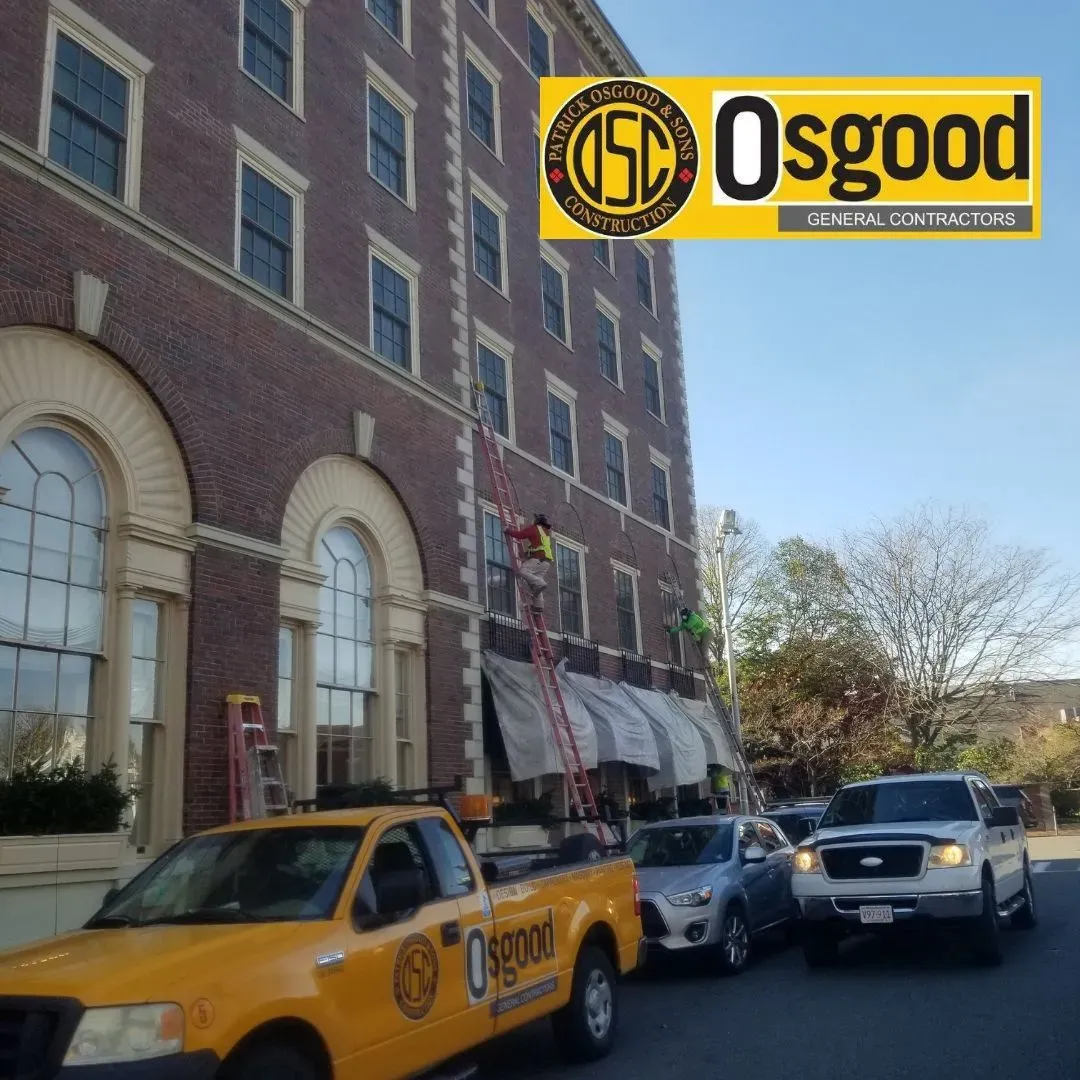 A yellow Osgood truck is parked in front of a brick building.