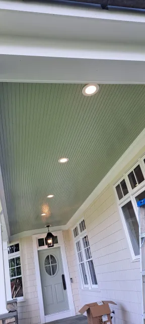 Covered front porch with mint-green patterned ceiling, white columns, and a glass front door.