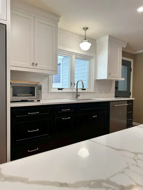 A kitchen with black cabinets and white counter tops