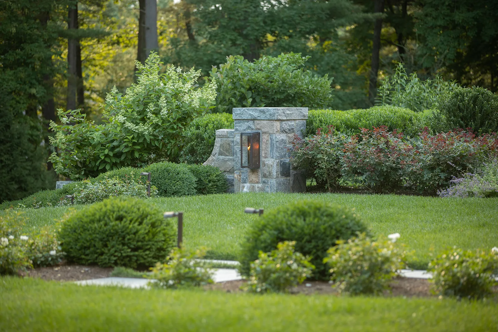 Stone lantern pier and clipped hedges in a woodland garden
