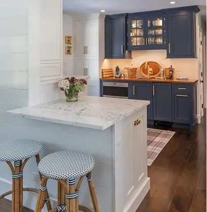 Bright kitchen with navy cabinets, white island, bar stools, and warm lighting